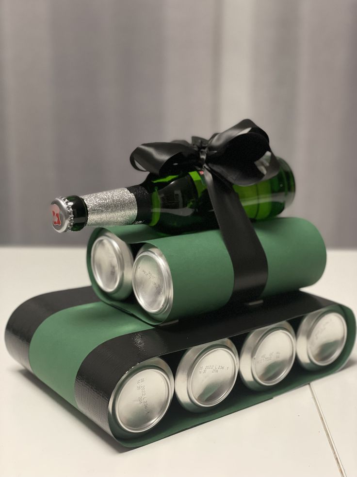 This may contain: three green and black rolled up batteries with a bottle of wine in the middle on top