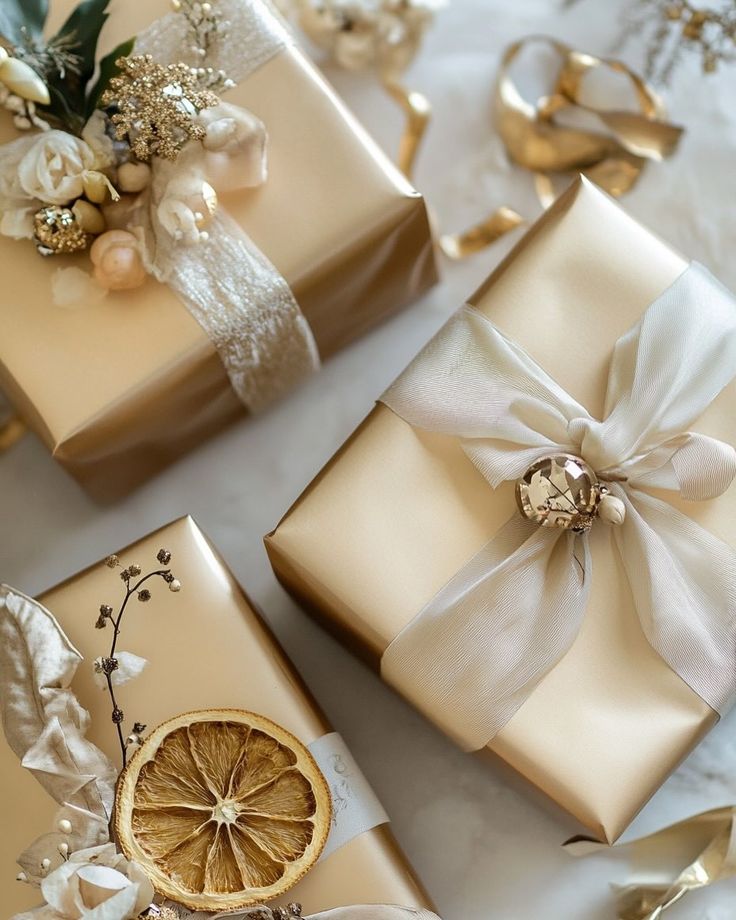 This may contain: three wrapped presents with ribbons and bows on them, sitting next to an orange slice