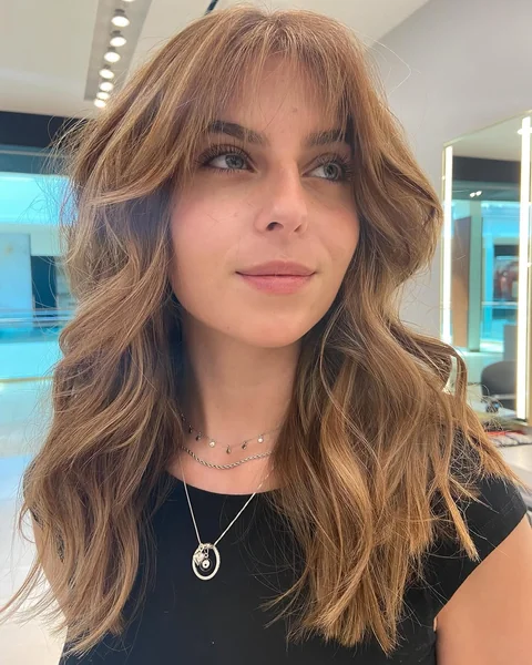 Voluminous Bronde Waves with Feathered Curtain Bangs
