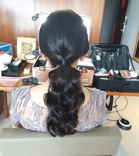 Textured Low Ponytail with Loose Braid and Floral Accent